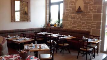 A restaurant with stone walls, wooden tables, and benches.