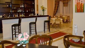 A hotel lobby with a bar area, dining tables, and chairs. - Alexiou Hotel (Kalabaka)