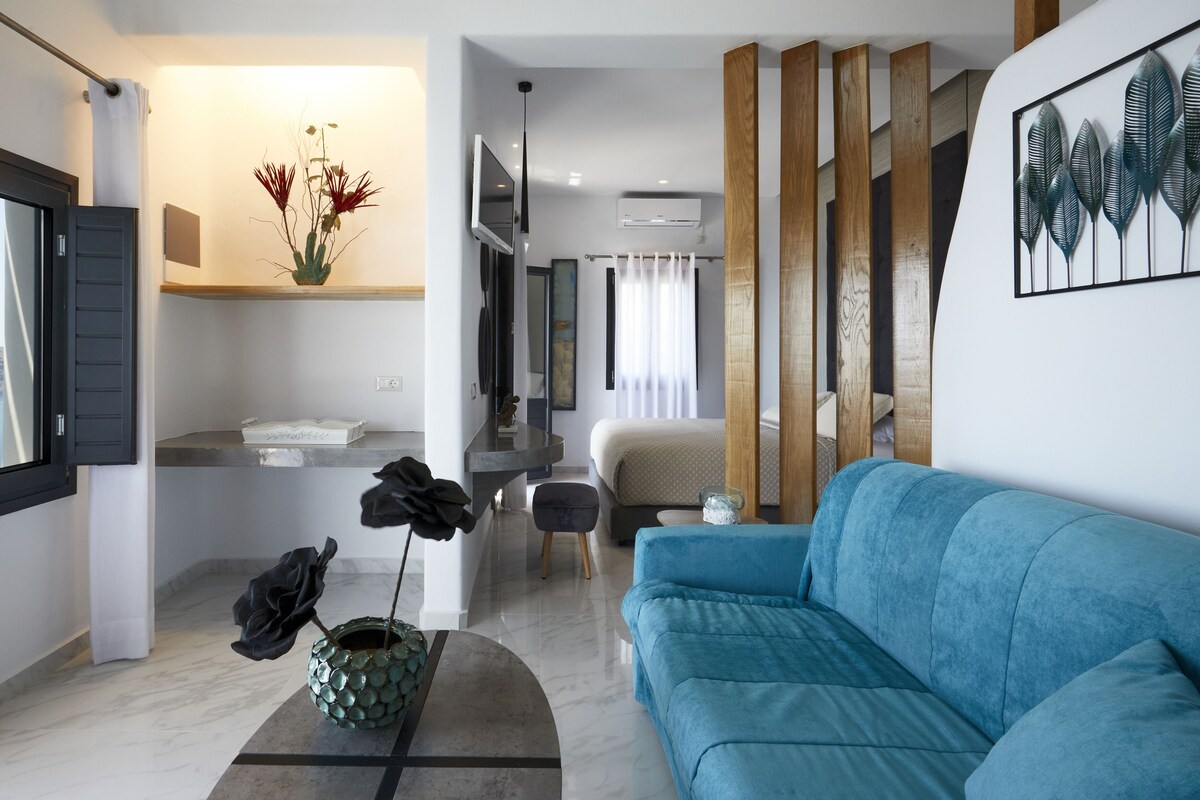 A modern living room with a blue sofa, a coffee table with a vase, and a view of the city through a window.