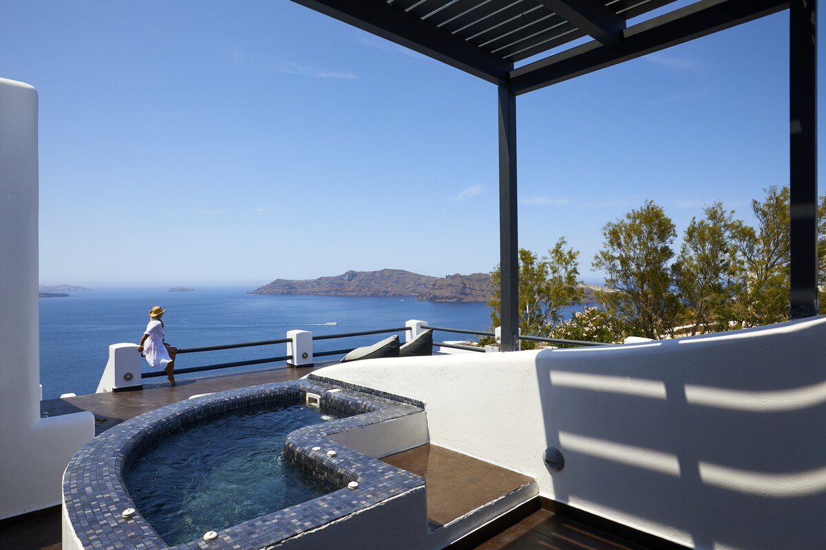 A modern outdoor hot tub area with a view of the sea and distant mountains.