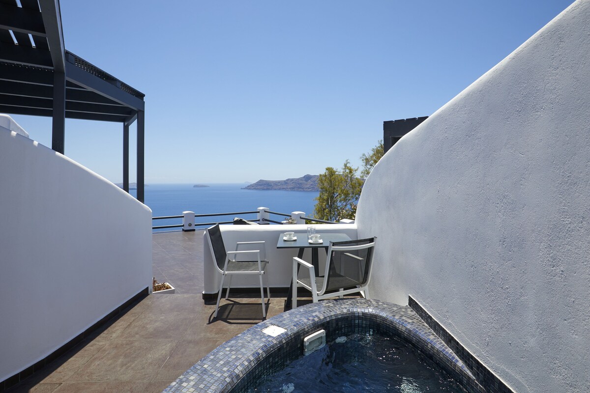 A rooftop terrace with a hot tub, dining table, chairs, and a view of the sea.