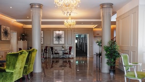 A lobby with a chandelier, columns, a reception desk, and seating areas. - Brook Lodge Boutique Hotel (Killarney)