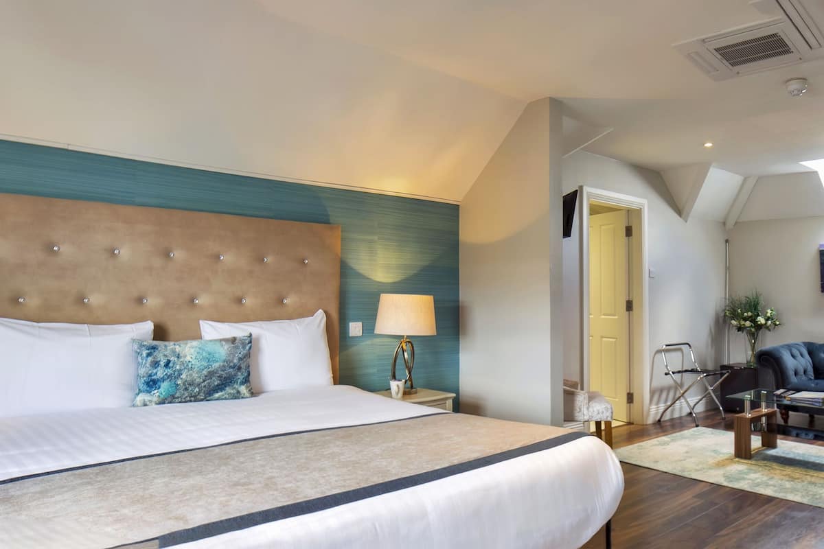 Une chambre d’hôtel avec un grand lit, un canapé bleu, une table basse et un tableau au mur.