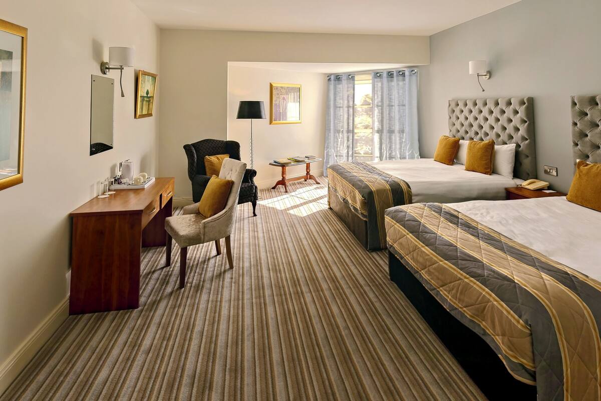 Une chambre d’hôtel avec deux lits, un bureau, une chaise et une petite table.