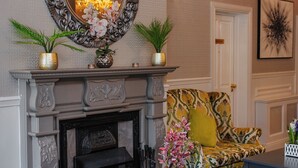 A room with a fireplace, a sofa, a table, and a mirror. - Brook Lodge Boutique Hotel (Killarney)