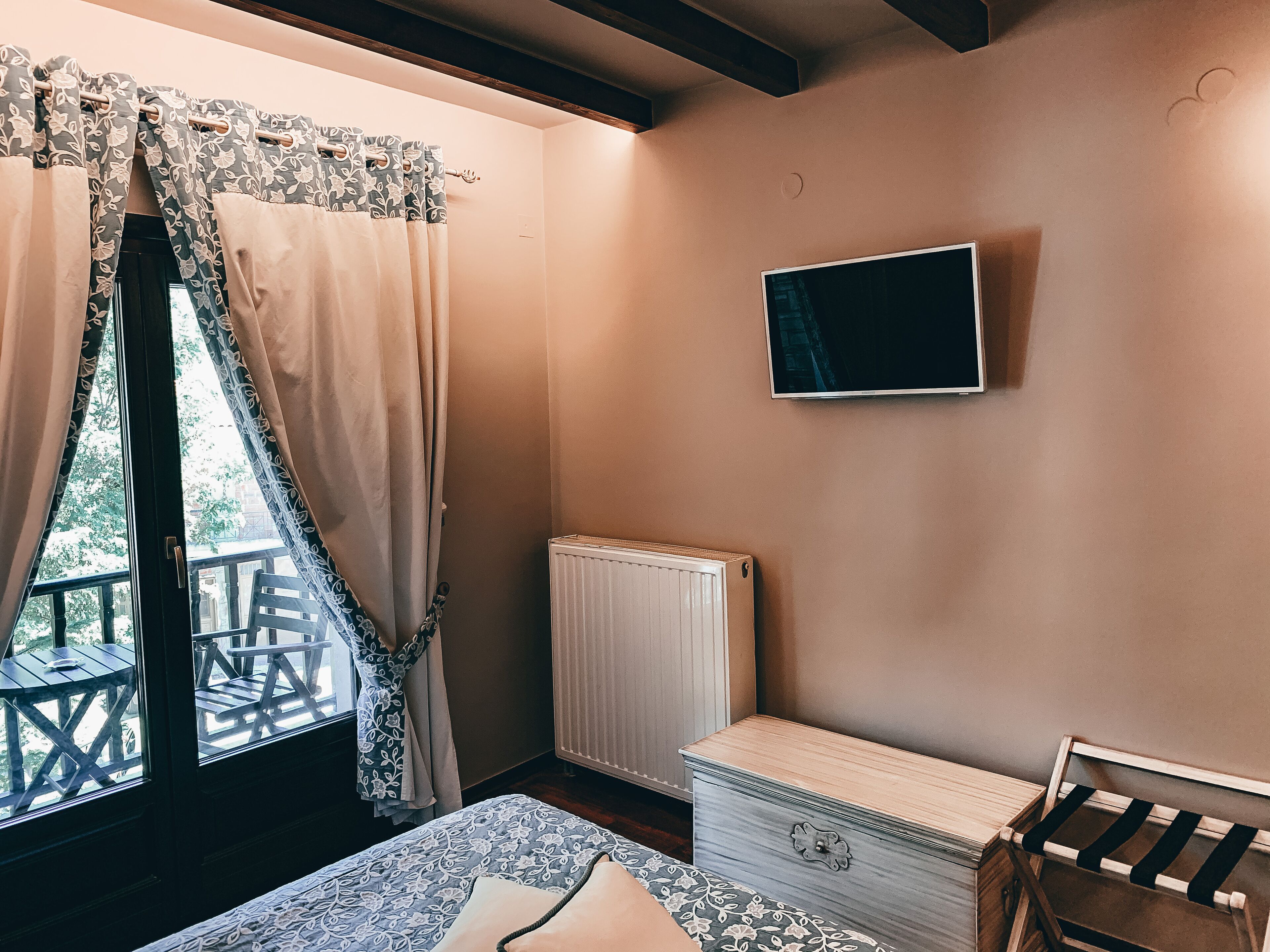 A bedroom with a bed, a dresser, a radiator, and a TV on the wall.