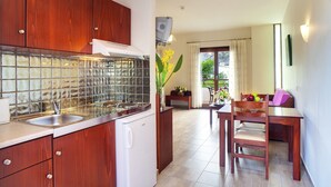 A compact kitchen with wooden cabinets, a stainless steel sink, and a tiled backsplash. - Syia Hotel (Kantanos-Selino)