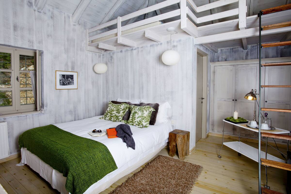 Een slaapkamer met een bed, nachtkastje, lamp en raam.
