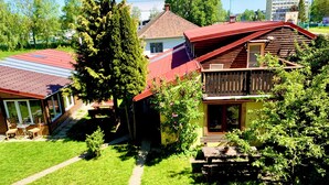 A two-story house with a red roof, a balcony, and a garden area with a table and chairs. - Pension Aqualand (Poprad)