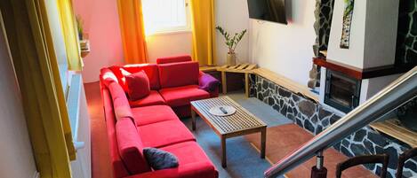 Una sala de estar con un sofá rojo, una mesa de centro, un televisor y una chimenea.