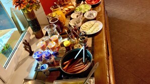 A buffet table with various food items and a pot of sausages. - Pension Aqualand (Poprad)