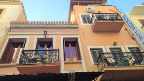 A multi-story building with balconies, a visible air conditioning unit, and a sign with text. - Diporto (Chania)