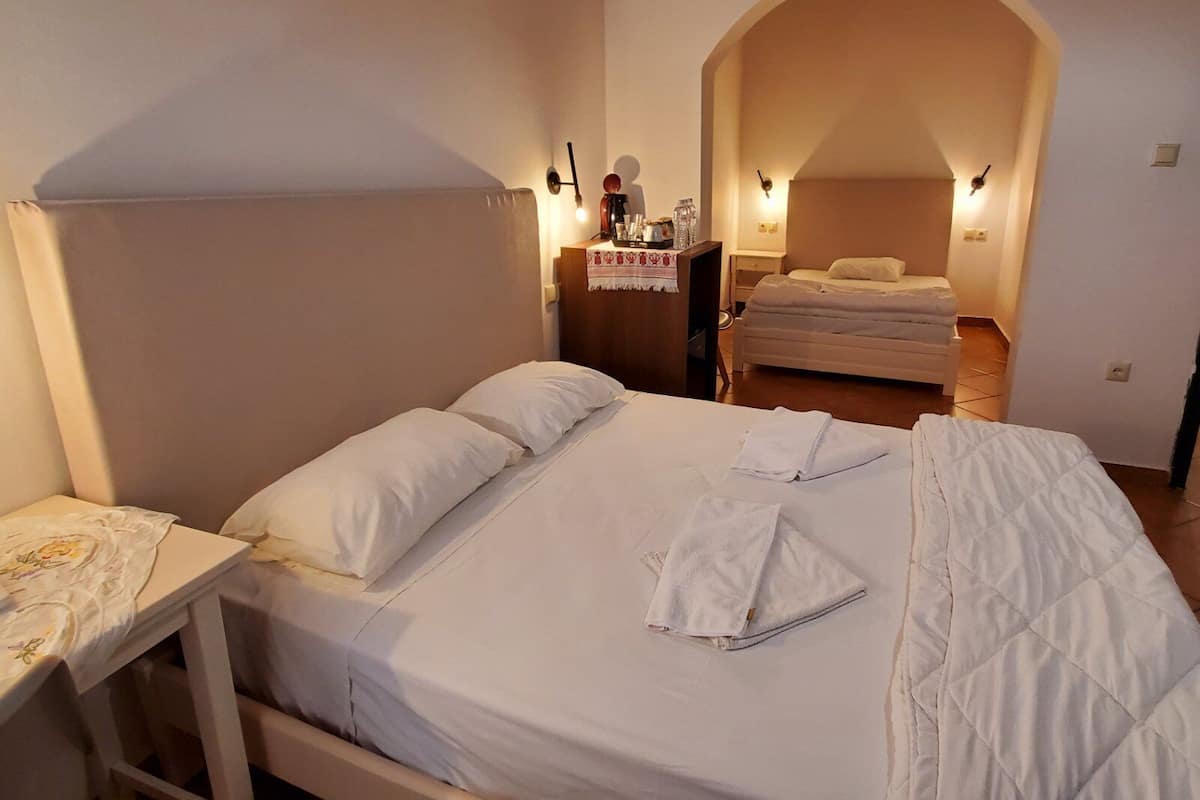 A bedroom with a bed, a nightstand, a table, and a mirror.