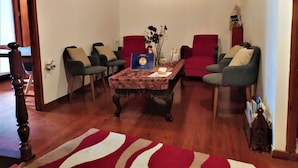 A living room with a wooden floor, a red and white striped area rug, a coffee table with a vase of flowers, and two red armchairs. - Diporto (Chania)