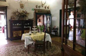 A dining area with a table set for two, a wooden cabinet with glassware, and antler decorations on the wall. - Rezydencja Bialy Jar (Karpacz)