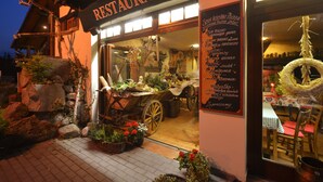 A restaurant with a rustic exterior, a wooden signboard, and a menu displayed outside. - Rezydencja Bialy Jar (Karpacz)