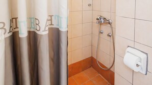 Ein Badezimmer mit Dusche, Toilette und Fenster.