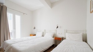 Ein Hotelzimmer mit zwei Betten, einem Fenster mit Vorhängen und einem Nachttisch mit Lampe.