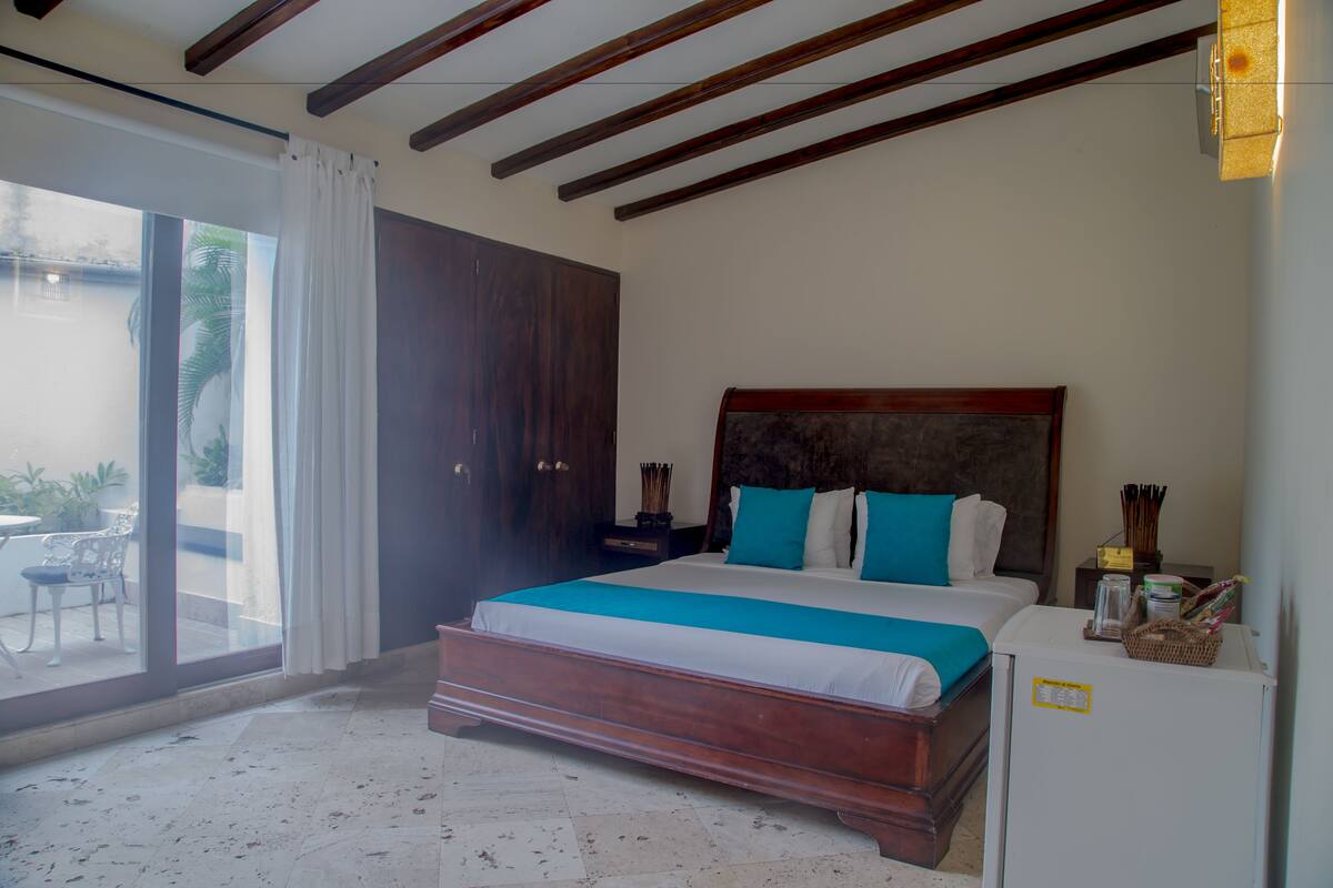 Ein Schlafzimmer mit einem großen Bett, einem hölzernen Kopfteil, einem Nachttisch und einem Kühlschrank.