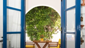 An open blue door leading to a room with a stone floor, a wooden table, and two yellow chairs.
