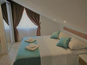 A bedroom with a bed, pillows, and a folded towel on the bed. - Sea Apartments Slano (Dubrovacko Primorje)