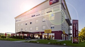 A Dream Inn Hotel with a cafe and bistro, a bike parked outside, and a clear sky. - Dream Inn Hotel Regensburg (Tegernheim)