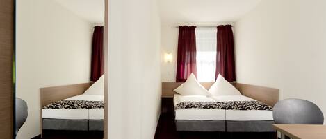 Quarto de hotel com cama, escrivaninha e cadeira.