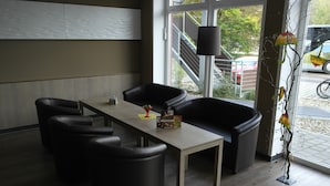 A modern meeting room with a long table, four black chairs, and a decorative plant. - Dream Inn Hotel Regensburg (Tegernheim)