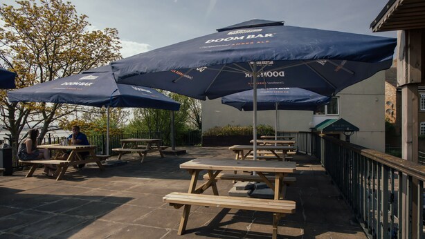 Mesas de picnic y sombrillas al aire libre, con el texto "DOOM BAR".