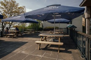 Mesas de picnic y sombrillas al aire libre, con el texto "DOOM BAR".