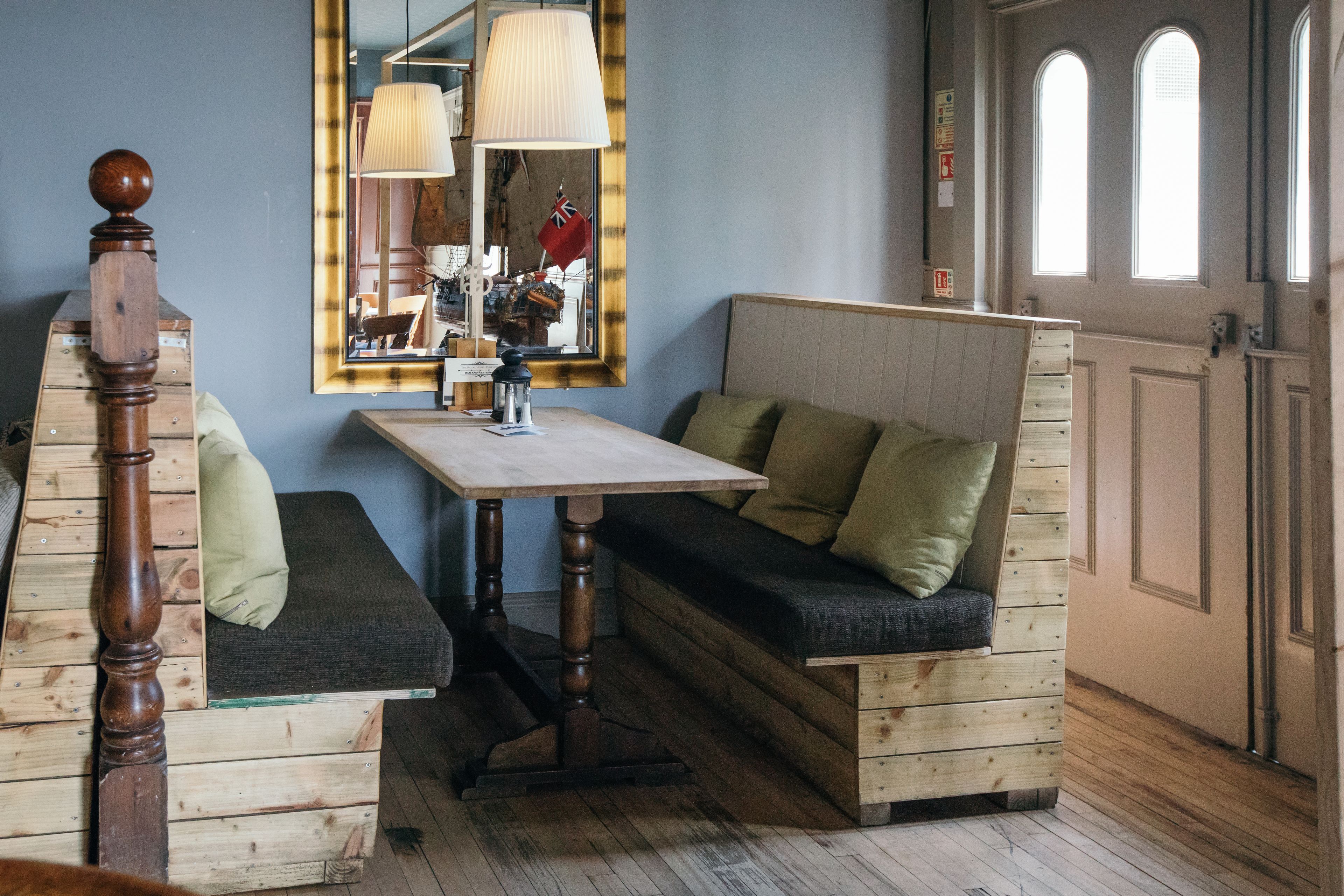 Um quarto aconchegante com um banco de madeira, uma mesa e um espelho.
