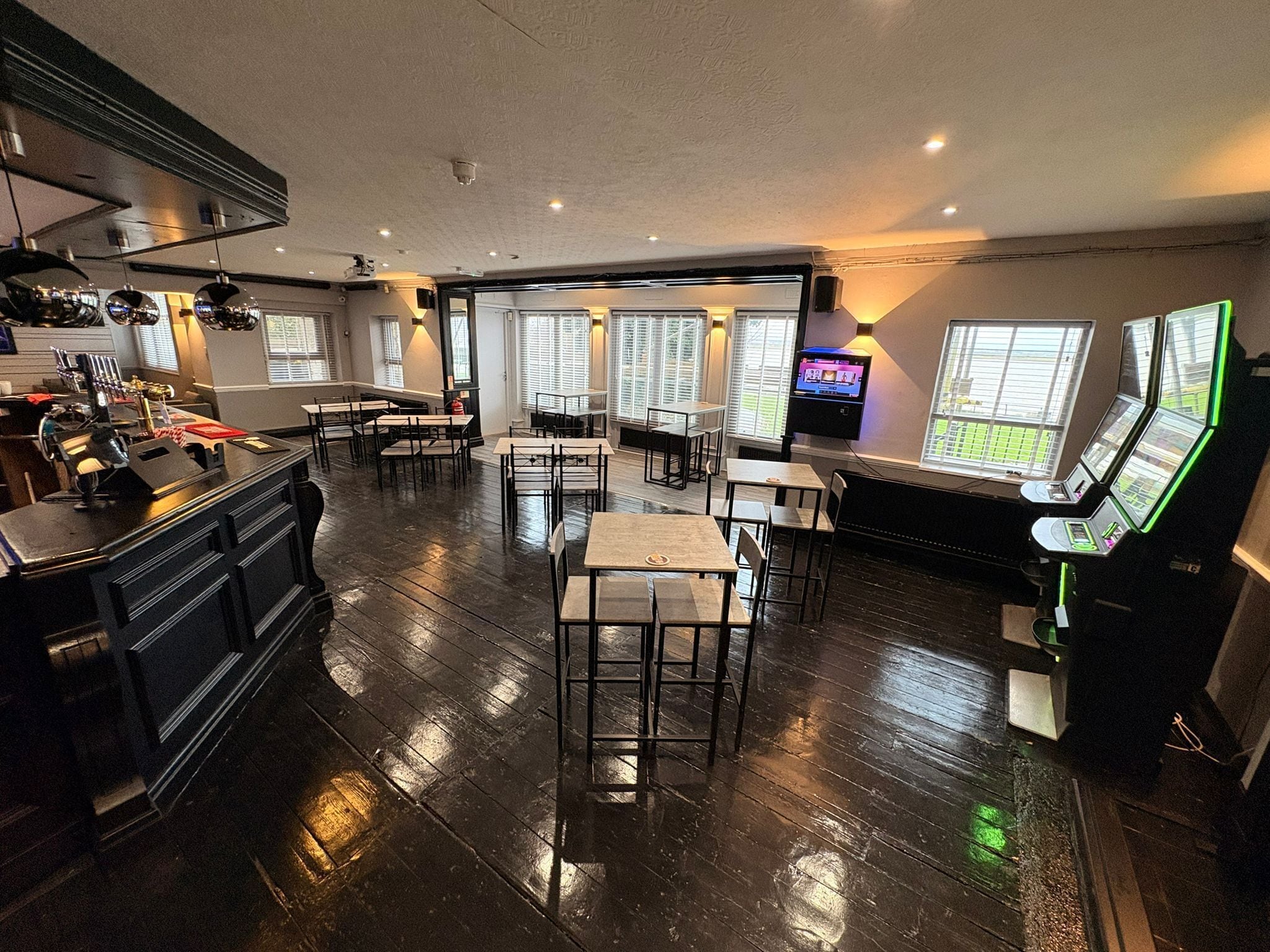 A spacious restaurant with high ceilings, wooden flooring, and multiple tables and chairs.