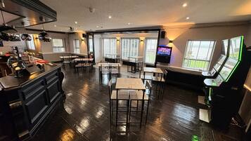 A spacious restaurant with high ceilings, wooden flooring, and multiple tables and chairs.