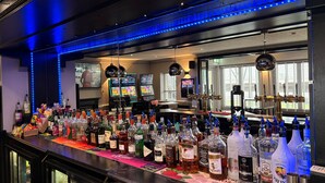 Zona de bar con varias botellas de licor, un jukebox y un espejo grande.