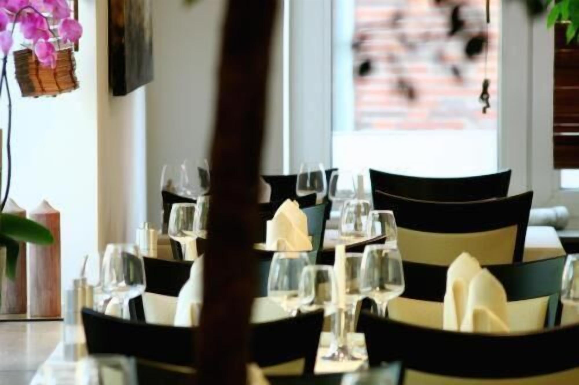 A restaurant setting with tables set for dining, chairs, and wine glasses.