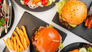 Une table avec un hamburger, des frites et une salade.