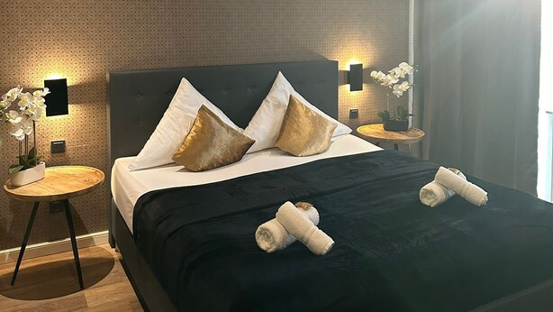 Une chambre d’hôtel moderne avec un grand lit, deux tables de chevet et une petite table d’appoint.