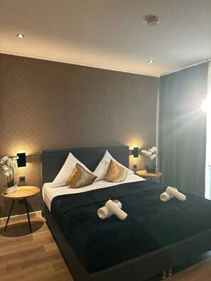 A modern hotel room with a large bed, two bedside tables, and a nightstand. - Hotel akazienhof (Duisburg)