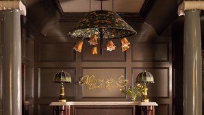 A reception area with a dark wood reception desk, a chandelier with multiple light fixtures, and a sign that reads 'Marine & Lane Hotels & Resorts'. - Portrush Adelphi  (Portrush)