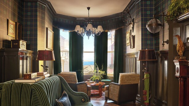 A room with a green sofa, a small table with a vase, and a lamp. - Portrush Adelphi  (Portrush)