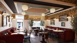 A spacious lounge area with red sofas, round tables, and hanging light fixtures. - Portrush Adelphi  (Portrush)