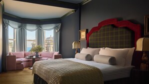 A hotel room with a large bed, a sofa, a small table, and a view of the city. - Portrush Adelphi  (Portrush)