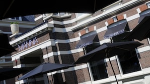 Un edificio con un letrero que dice 'MANN', sombrillas exteriores y fachada de ladrillo.