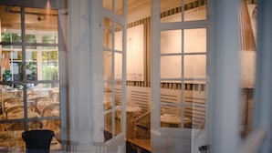 Un comedor con mesas y sillas, una escalera y una vista por la ventana.