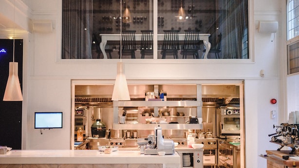 Una cocina moderna con electrodomésticos de acero inoxidable, una isla grande e iluminación colgante.