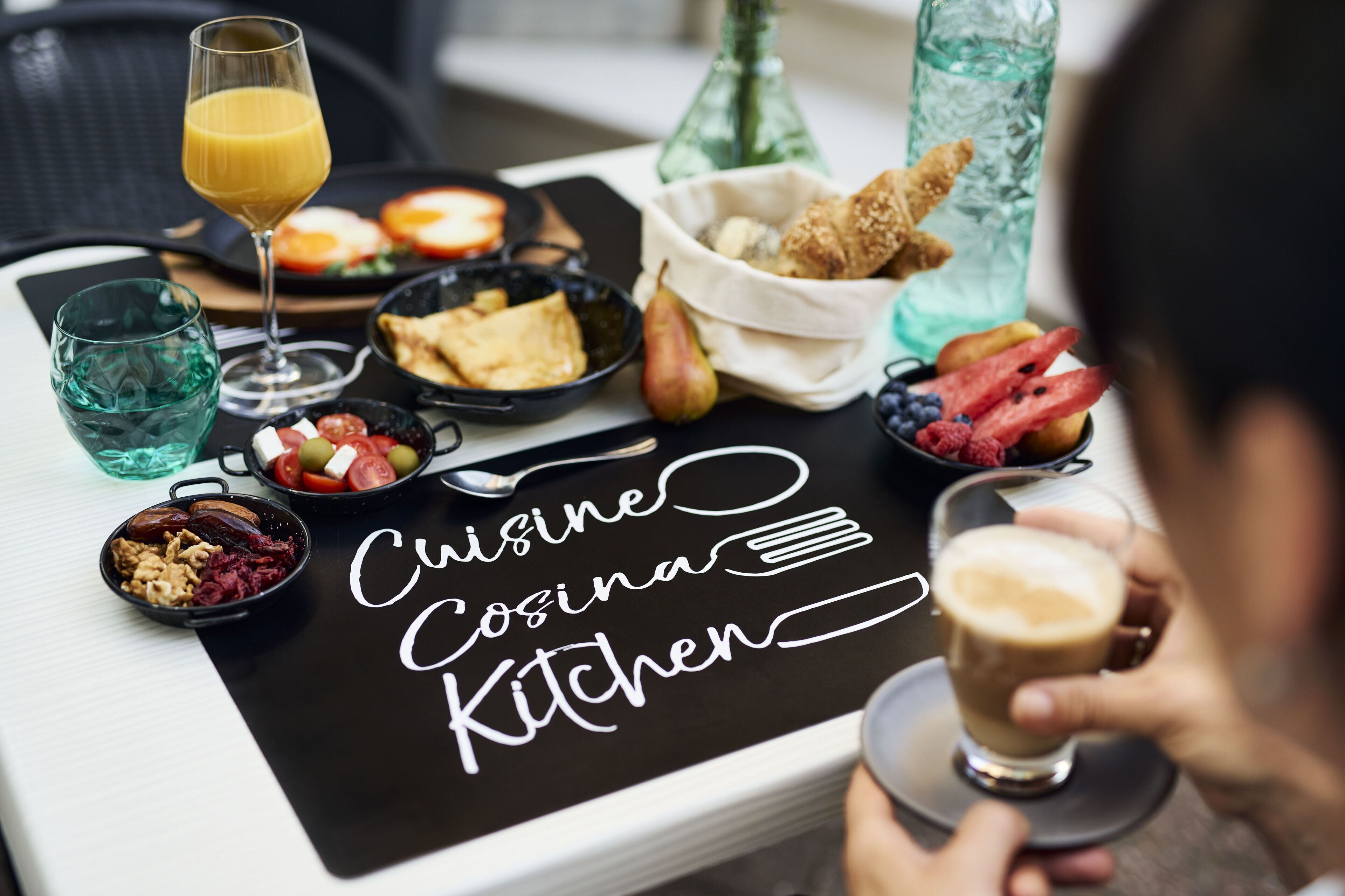 A breakfast setting with a variety of food items and a glass of orange juice on a tray.