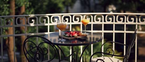 Una mesa con un vaso de jugo de naranja, un vaso de bebida roja y un plato de sandía y bayas.