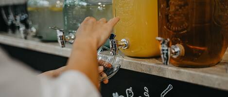 A hand reaching for a tap to fill a glass from a large container.