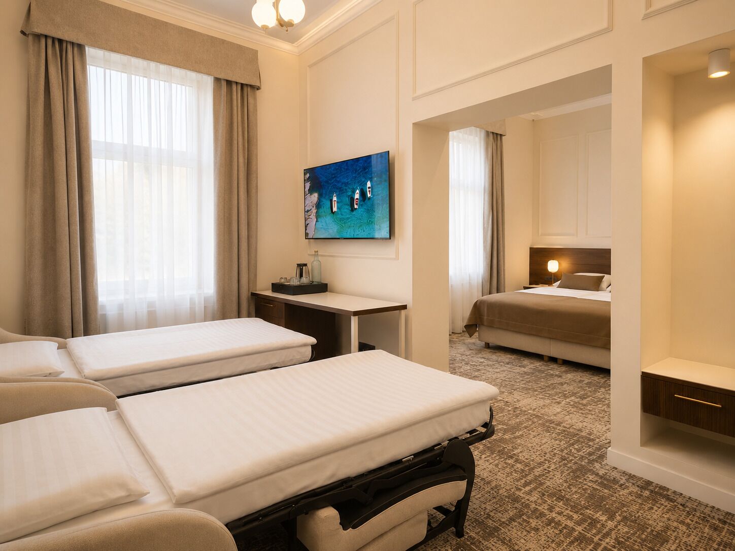 Una habitación de hotel con dos camas, un escritorio, un cuadro y una zona de dormitorio separada.