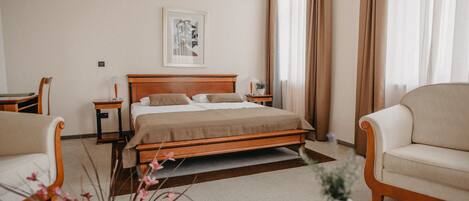 Una habitación de hotel con una cama, dos mesitas de noche, una silla, una pequeña mesa y una planta en maceta.